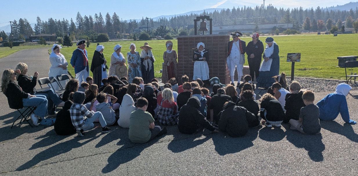 The Daughters of the American Revolution presenting to students in an outdoor setting.